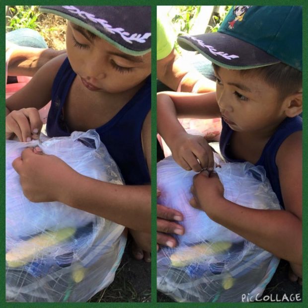 Four-year-old Daniel Bermio secures his grandfather's newly acquired fishing nets at Ayala Foundation's fishnet distribution, organized by NVC.