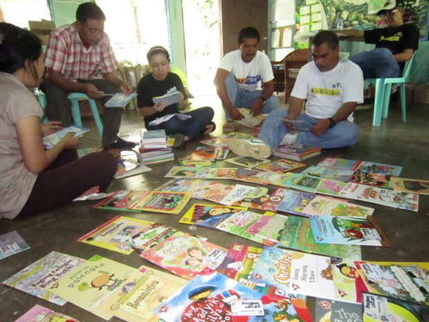 Cathee, center, sorting children's books for one of NVC's school support projects.