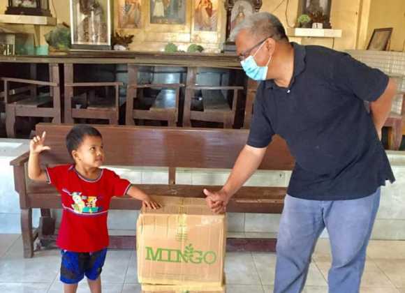  Father Louie and Ruben, one of the young recipients of Mingo, recreate Abram′s cartoon during Mingo distribution day.